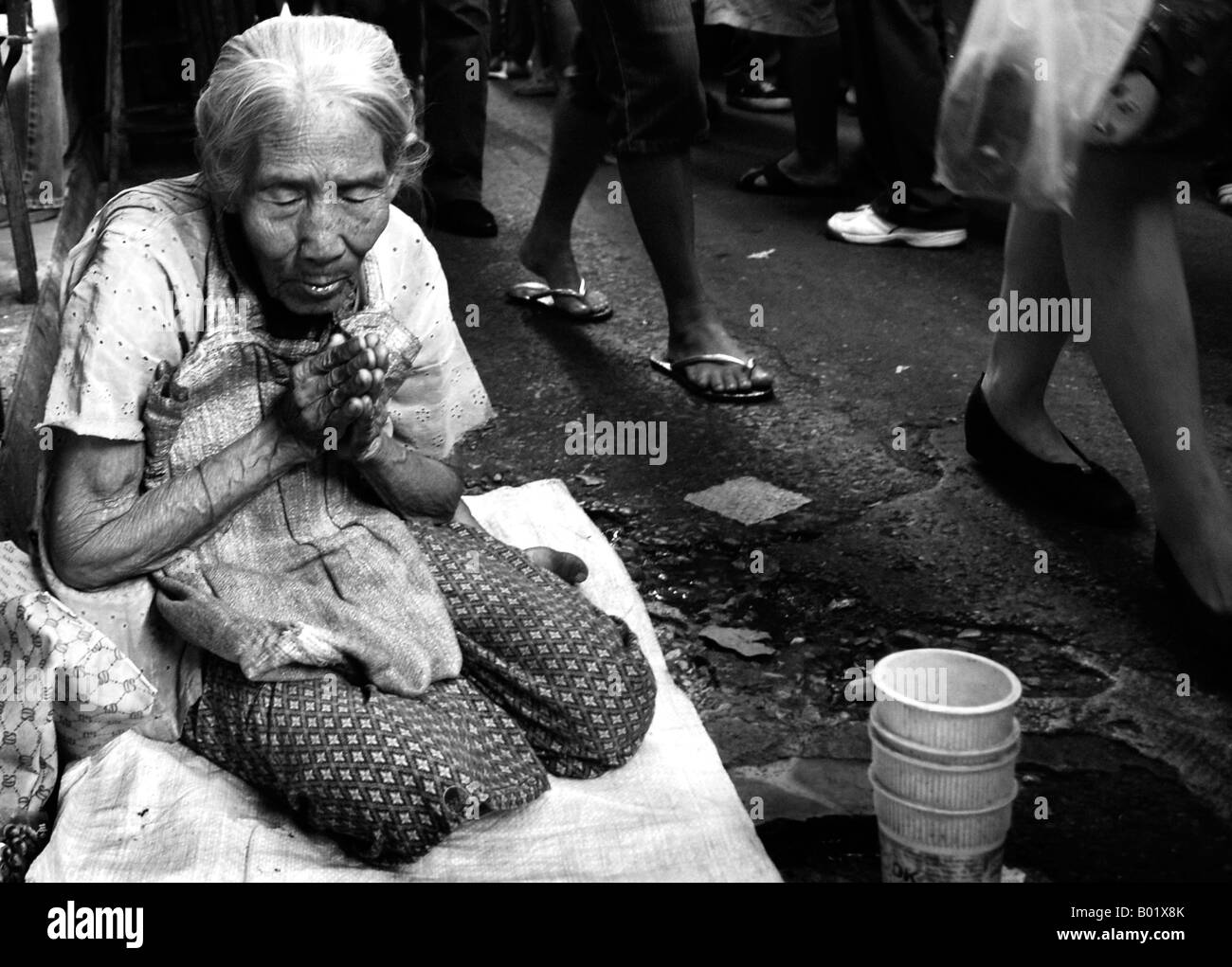 Signora tailandese mendica per soldi in un mercato per le strade di Bangkok in Thailandia. Foto Stock