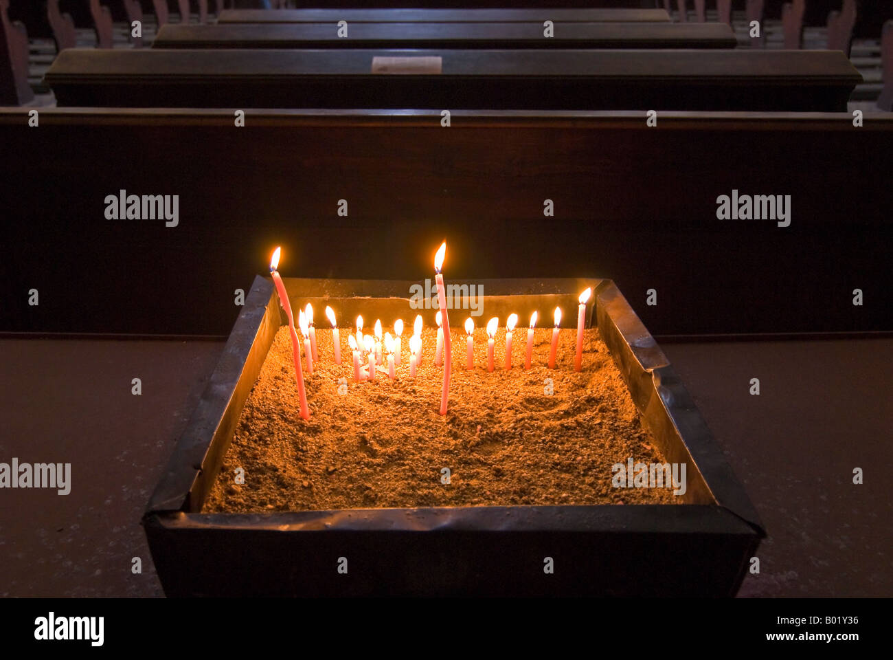 Chiudere orizzontale fino di religiosi 'candele votive' acceso all'interno di una chiesa oscura. Foto Stock