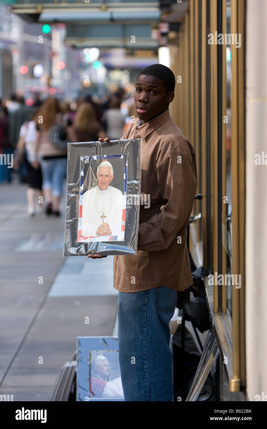 Un giovane uomo vende fotografie di Papa Benedetto XVI il 6th Ave in aprile 2008. Foto Stock