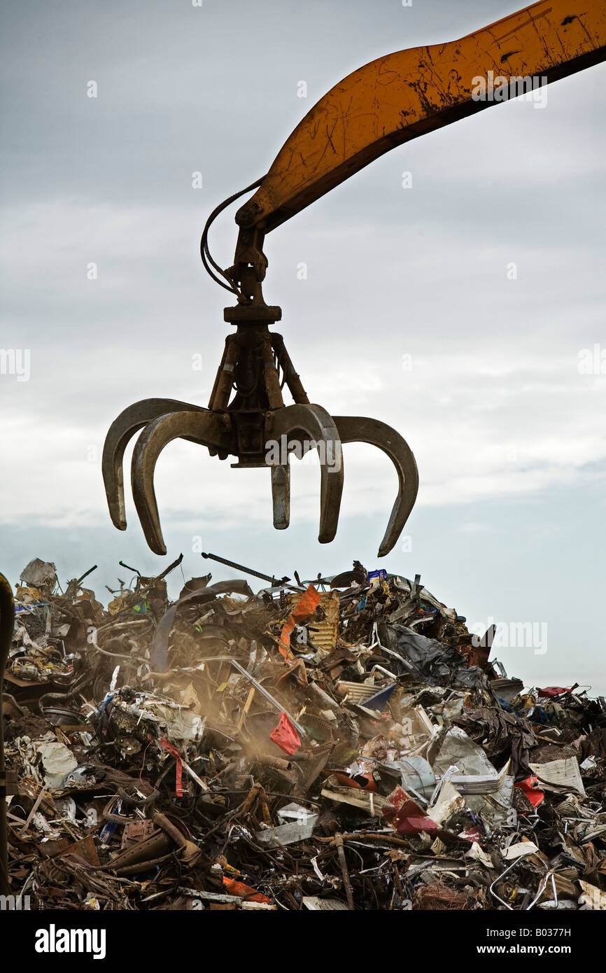 Una gru grab è oggetto di pratiche di dumping a carico su una pila di scarto. Foto Stock