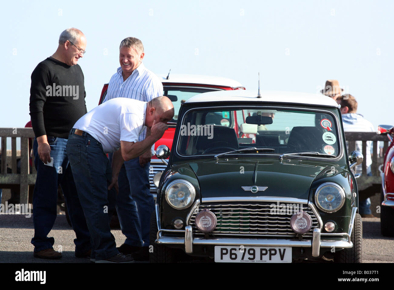 In un giorno d'estate tre uomini in stand by un classico Mini-Cooper Foto Stock