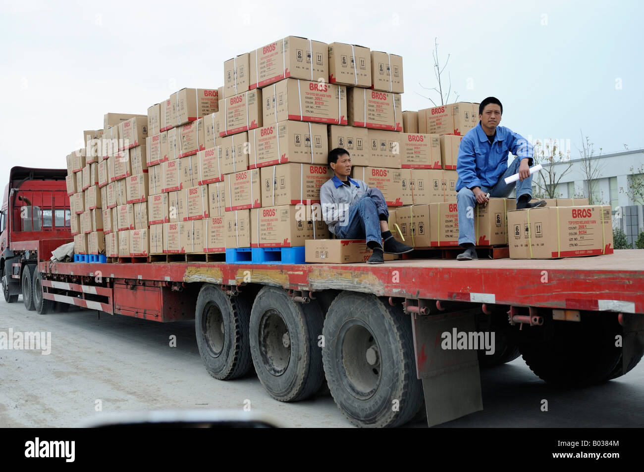 Due lavoratori cinesi su un veicolo piatto inoltro tinto filo melange di Ningbo nella provincia di Zhejiang Cina 19 Apr 2008 Foto Stock