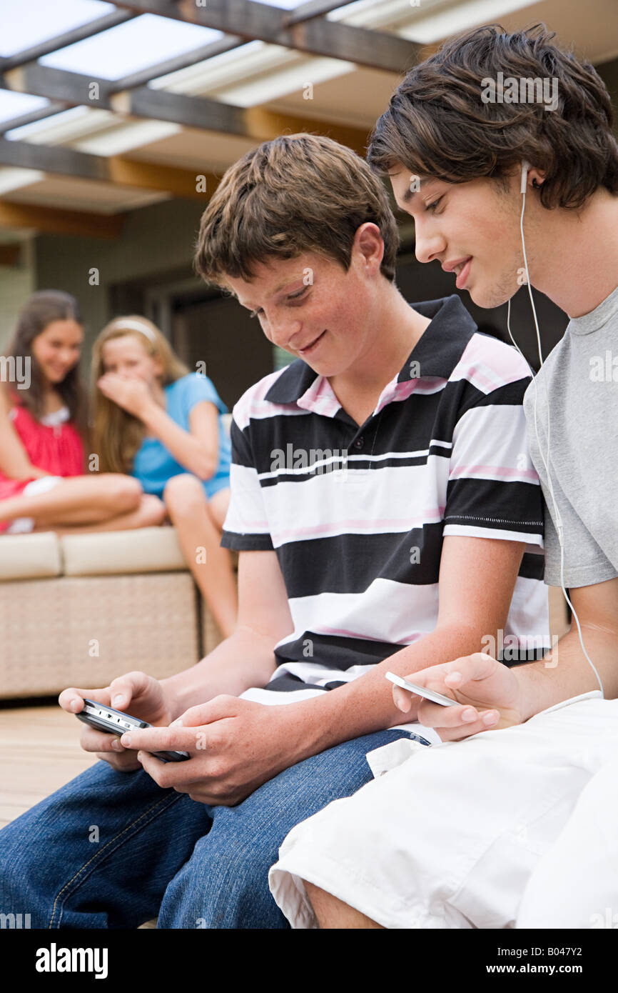 Ragazzi adolescenti l'ascolto di musica e la riproduzione di un video gioco Foto Stock