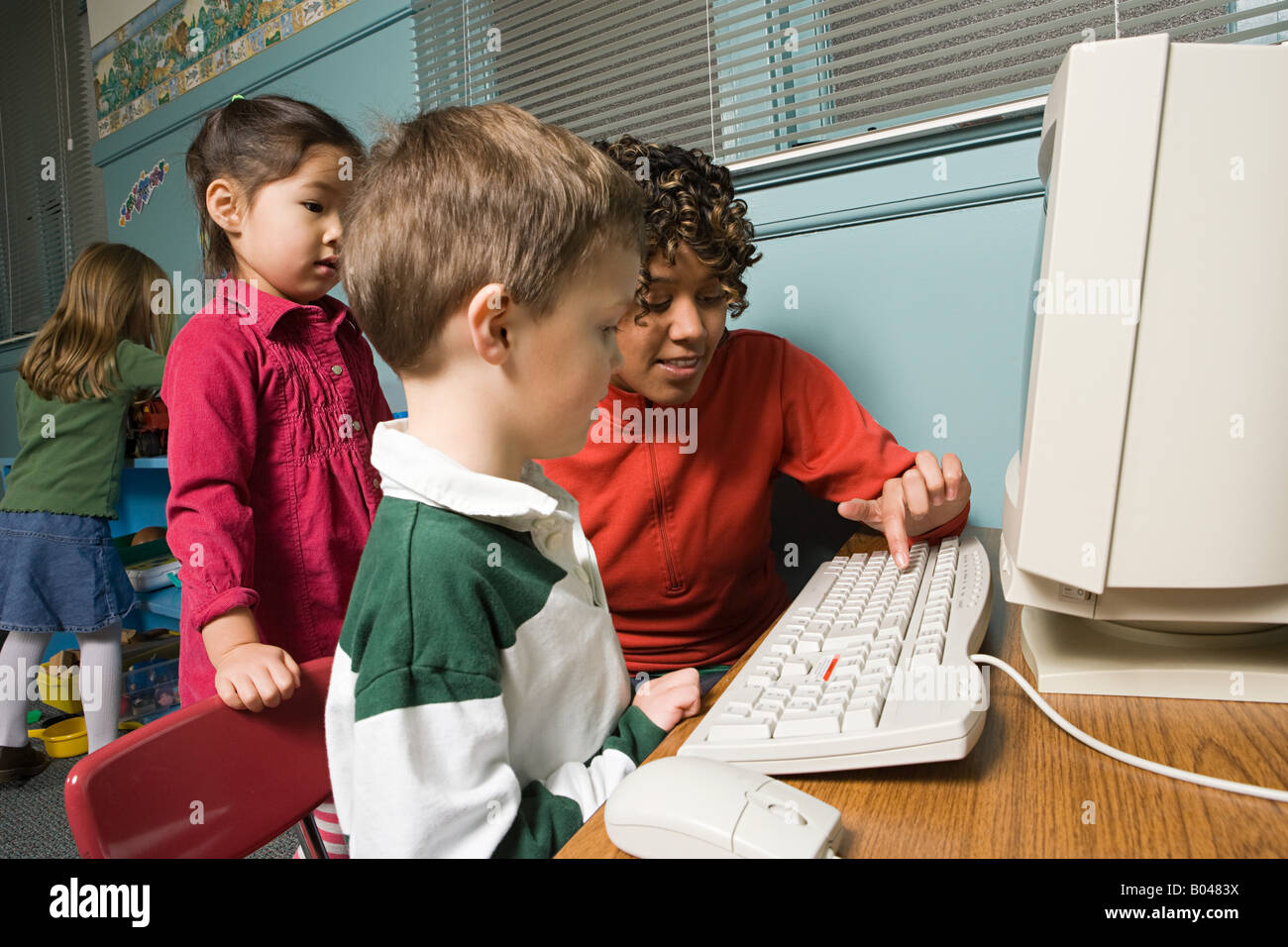 Un insegnante che mostra i suoi allievi come utilizzare un computer Foto Stock