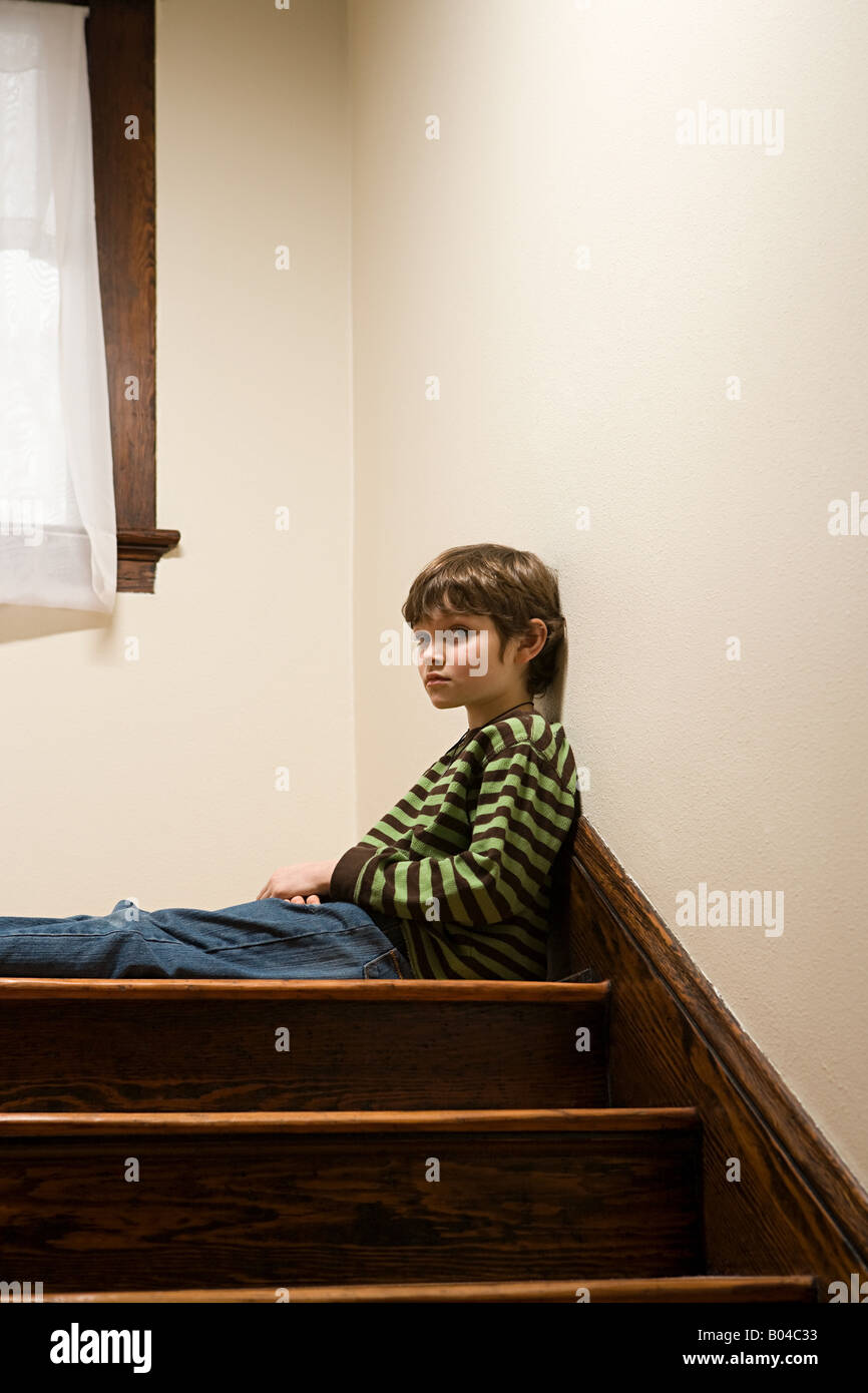 Un ragazzo seduto su scale Foto Stock