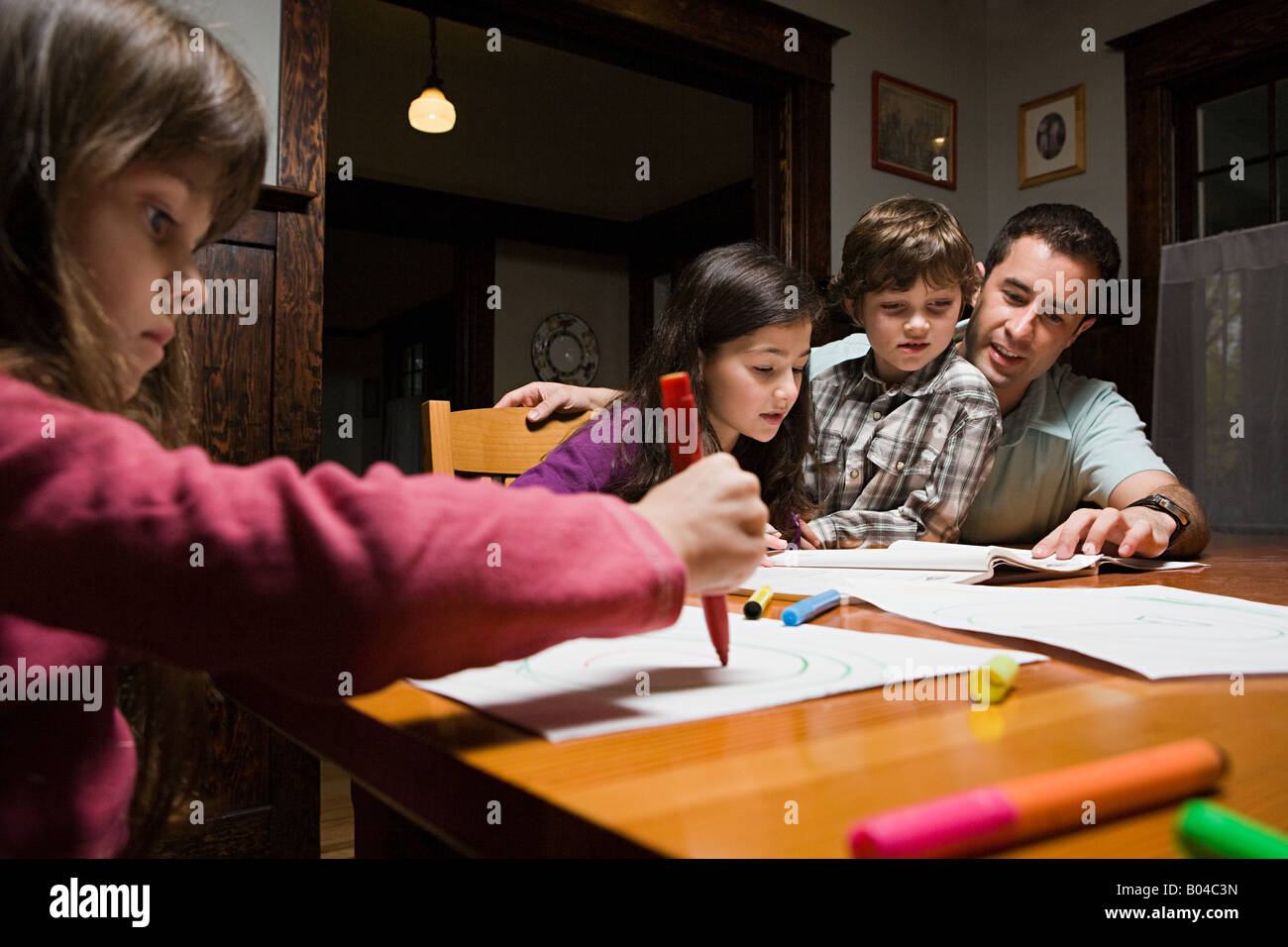 Un padre supervisionare i suoi bambini con i loro compiti Foto Stock