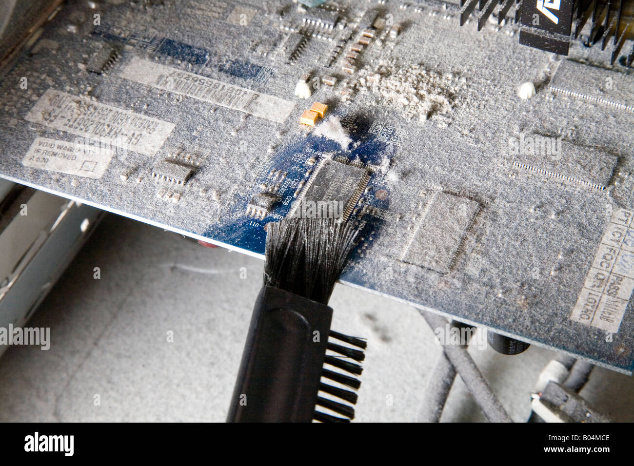 All'interno di un computer che mostra la polvere edificata sui componenti. un piccolo pennello viene utilizzato per pulire questa scheda grafica. Foto Stock