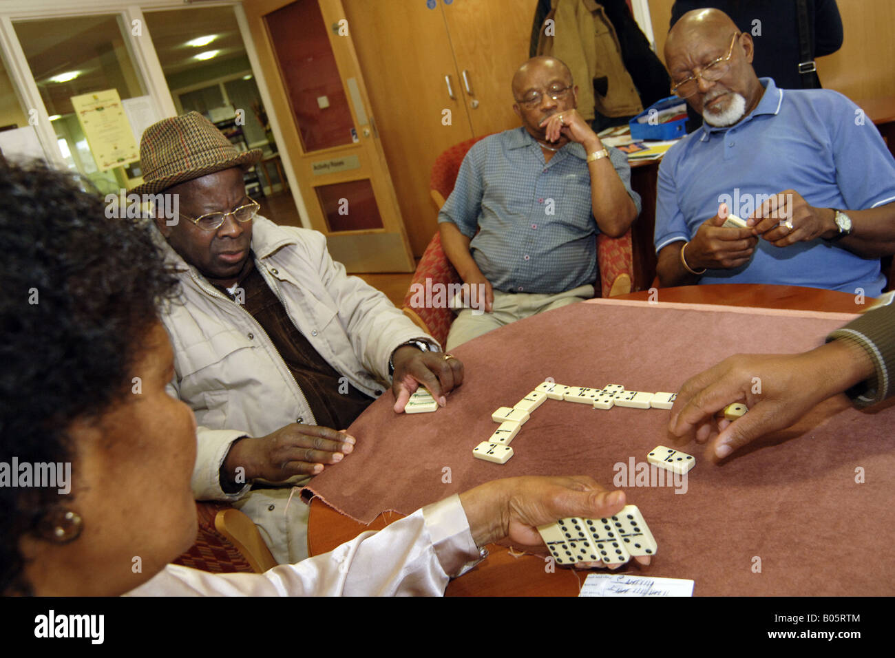 Le persone anziane GIOCA Domino a un multi culturale giorno centro Bradford Foto Stock