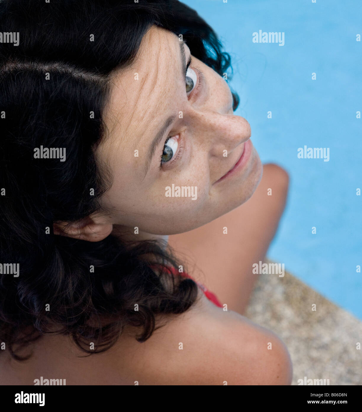 Giovane donna sulla piscina, sorride alla telecamera Foto Stock