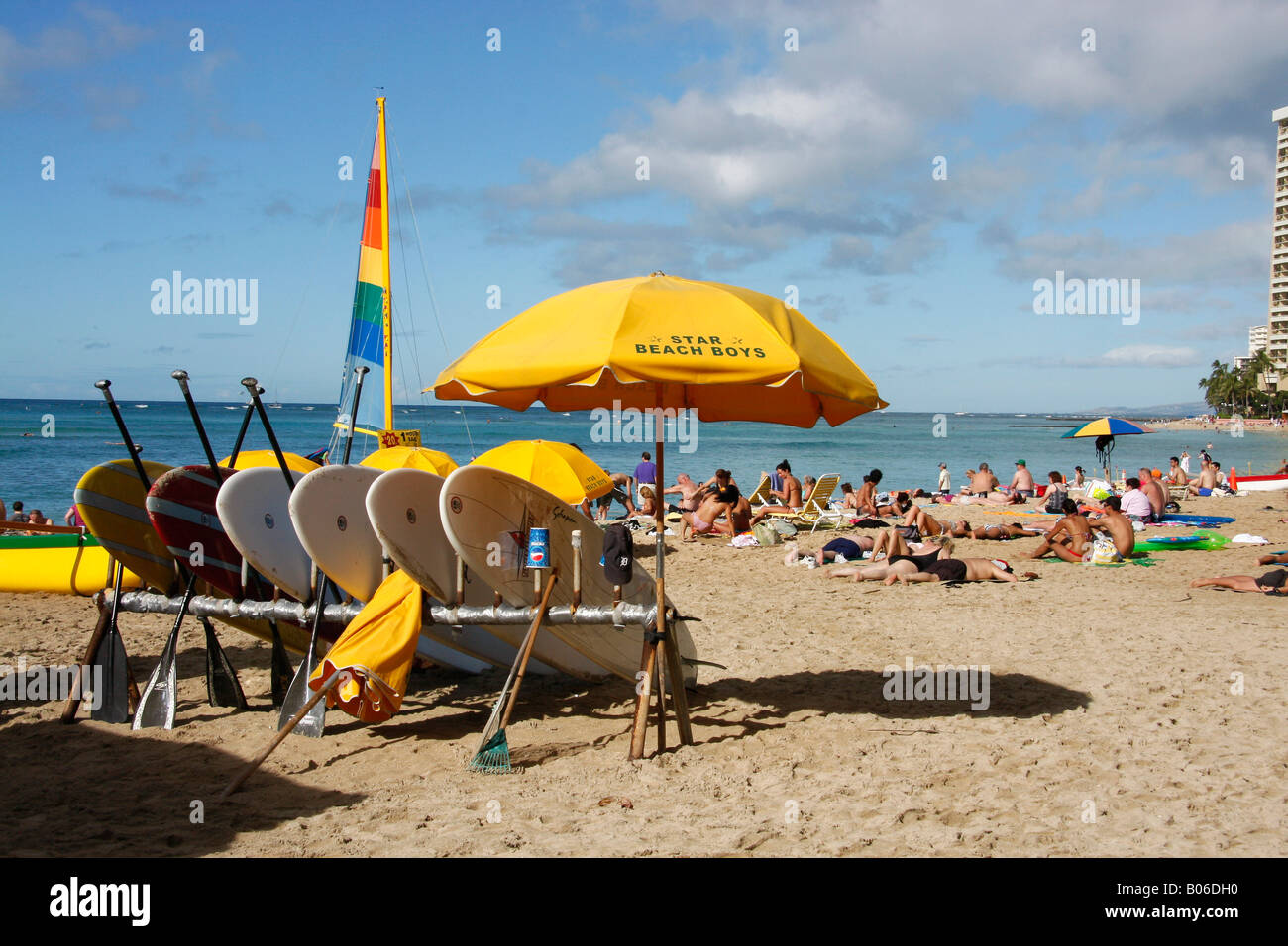 Pila di tavole da surf sulla spiaggia di Waikiki con lucertole da mare in background. Foto Stock