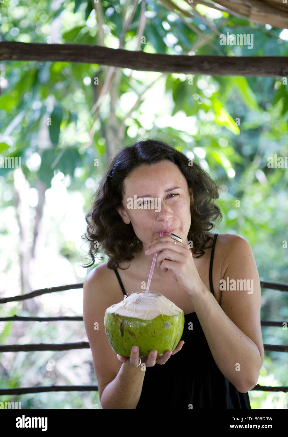 Giovane donna beve una noce di cocco Foto Stock