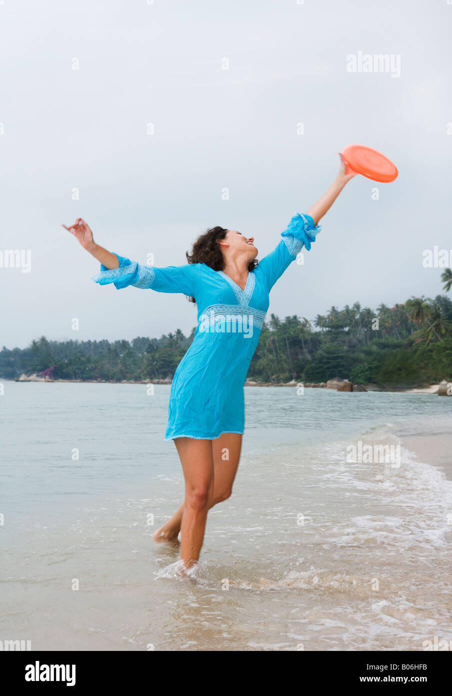 Giovane donna gioca frisbee sulla spiaggia Foto Stock