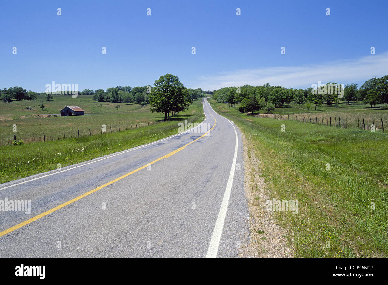 Un solitario strada scorre attraverso il paese di fattoria dei monti Ozark vicino a Eureka Springs Foto Stock