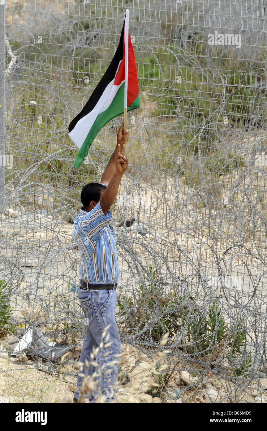 Un giovane uomo di innalzare la bandiera palestinese durante una manifestazione di protesta contro l'occupazione israeliana nel villaggio di Bilin, Palestina. Foto Stock