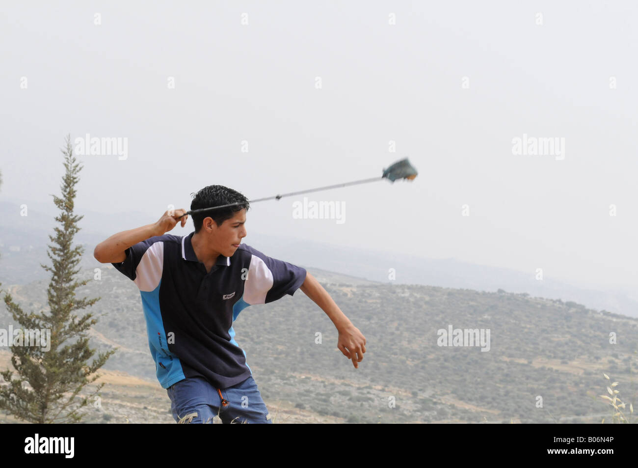 Un bambino palestinese un tiro sling shot durante una manifestazione di protesta contro il muro e occupazione nel villaggio di Bilin, Palestina. Foto Stock