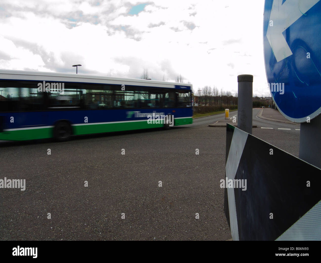 Un bus percorrendo una mini rotonda con un cartello stradale che indica la direzione in Swindon Foto Stock