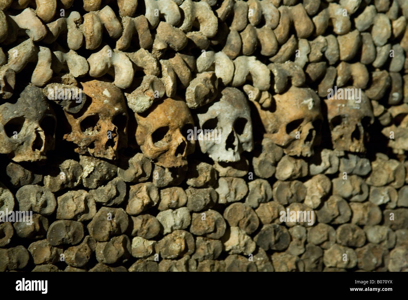 Teschi umani e ossa impilate in righe nelle catacombe sotterranee, Parigi, Francia. Foto Stock