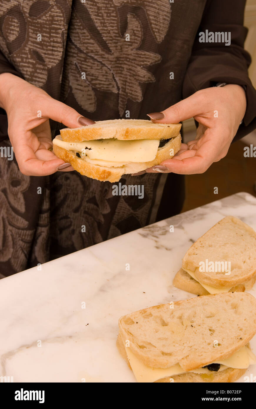 Primo piano della femmina caucasica Mani Diamante Nero tartufi sandwich con pane di pasta acida e formaggio fuso USA Foto Stock