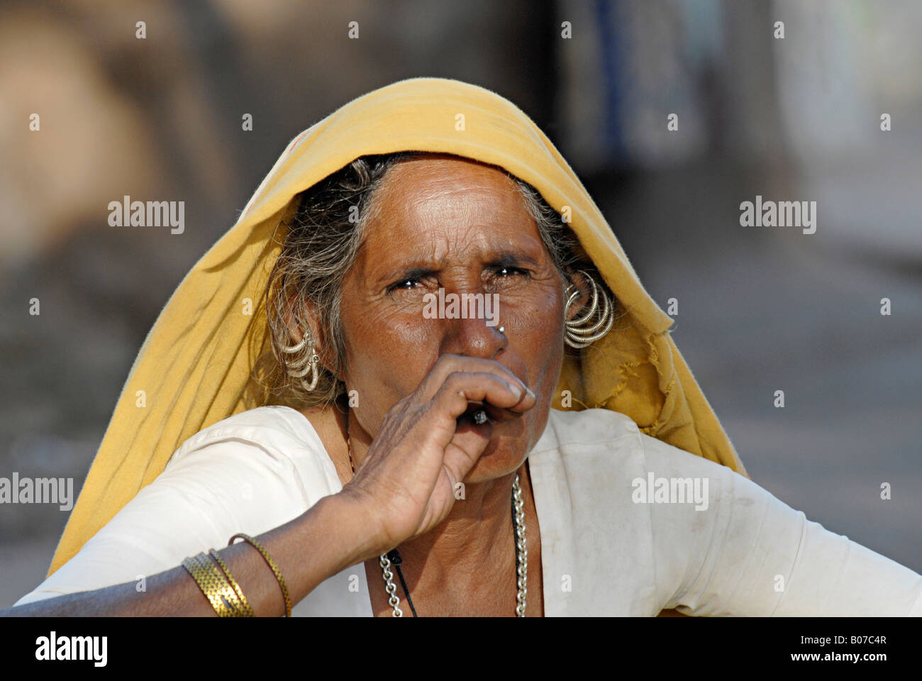 Close-up di una vecchia donna tribale fumatori bidi, un indiano a mano fatte di sigarette di tabacco o beedi foglie. Tribù Bhil Foto Stock