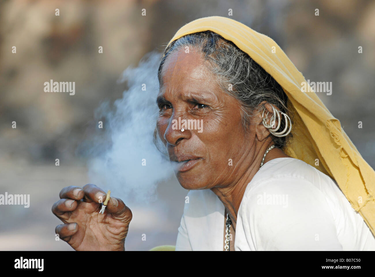 Il vecchio donna tribale fumatori bidi, un indiano a mano fatte di sigarette di tabacco o beedi foglie. Tribù Bhil Foto Stock