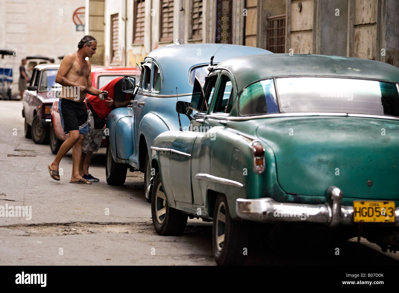 Due uomini cubani sono la riparazione di una vecchia vettura americana. Centro Habana. Centro di Havana. Cuba. Foto Stock