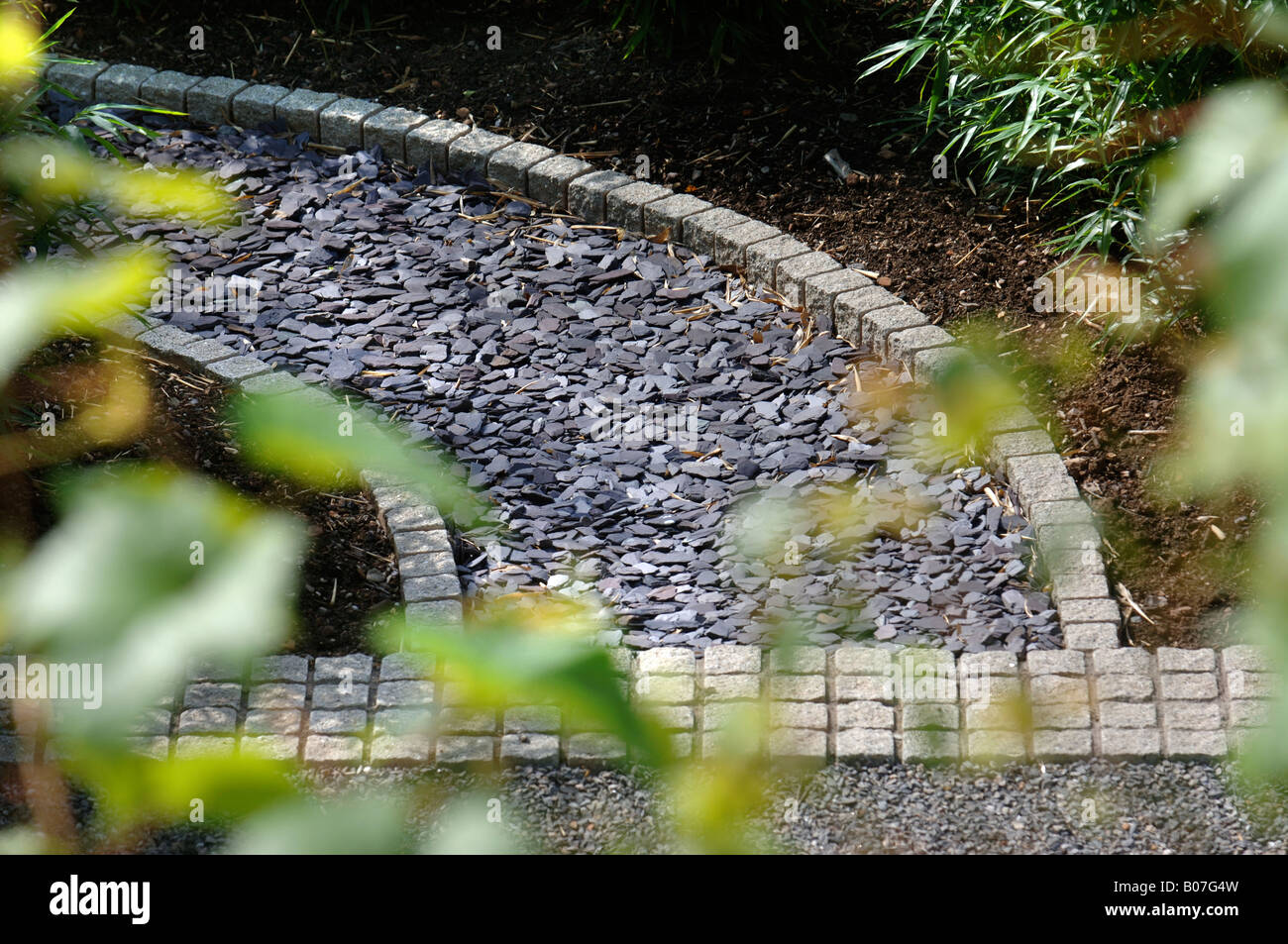 Un percorso posati con frammenti di ardesia e bordato con ciottoli di granito Foto Stock