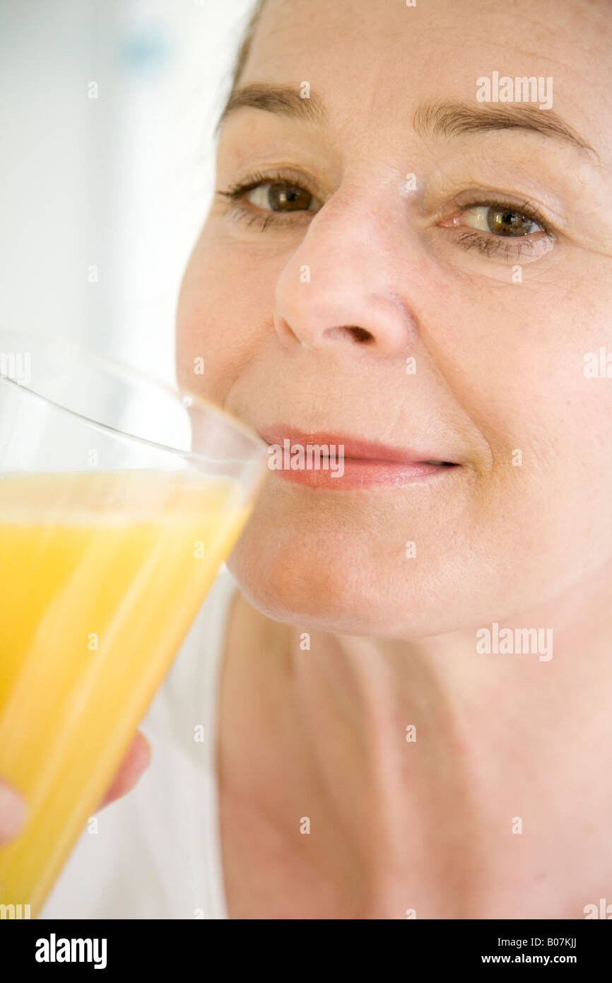 Donna matura di bere succo di arancia Foto Stock