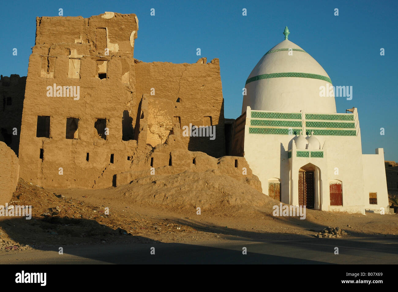 Una struttura di recente costruzione santuario islamico contrasta con le rovine di un vecchio edificio mudbrick vicino al Hawta in Yemen's Hadhramawt Foto Stock