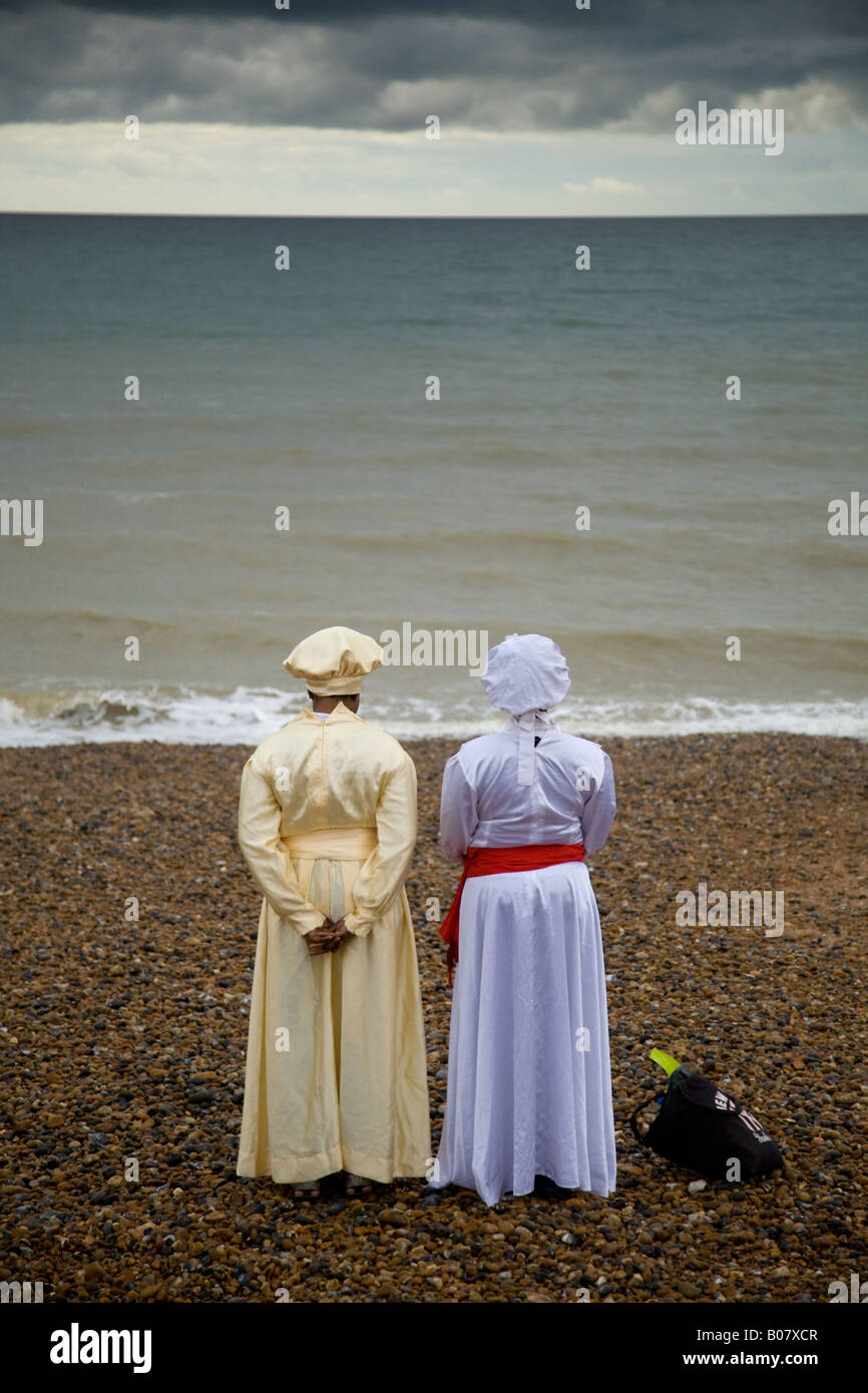 Due donne in costume religiosa guardando al mare a Brighton Seafront in anticipo di una full immersion battesimo in mare Foto Stock