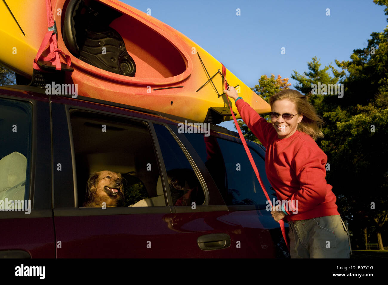 Donna unstraps kayak da portapacchi sul SUV Foto Stock
