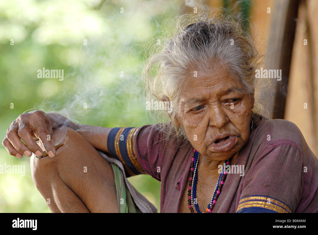 Vecchia donna fumatori bidi, un indiano a mano fatte di sigarette di tabacco o beedi foglie. Warli tribe Foto Stock