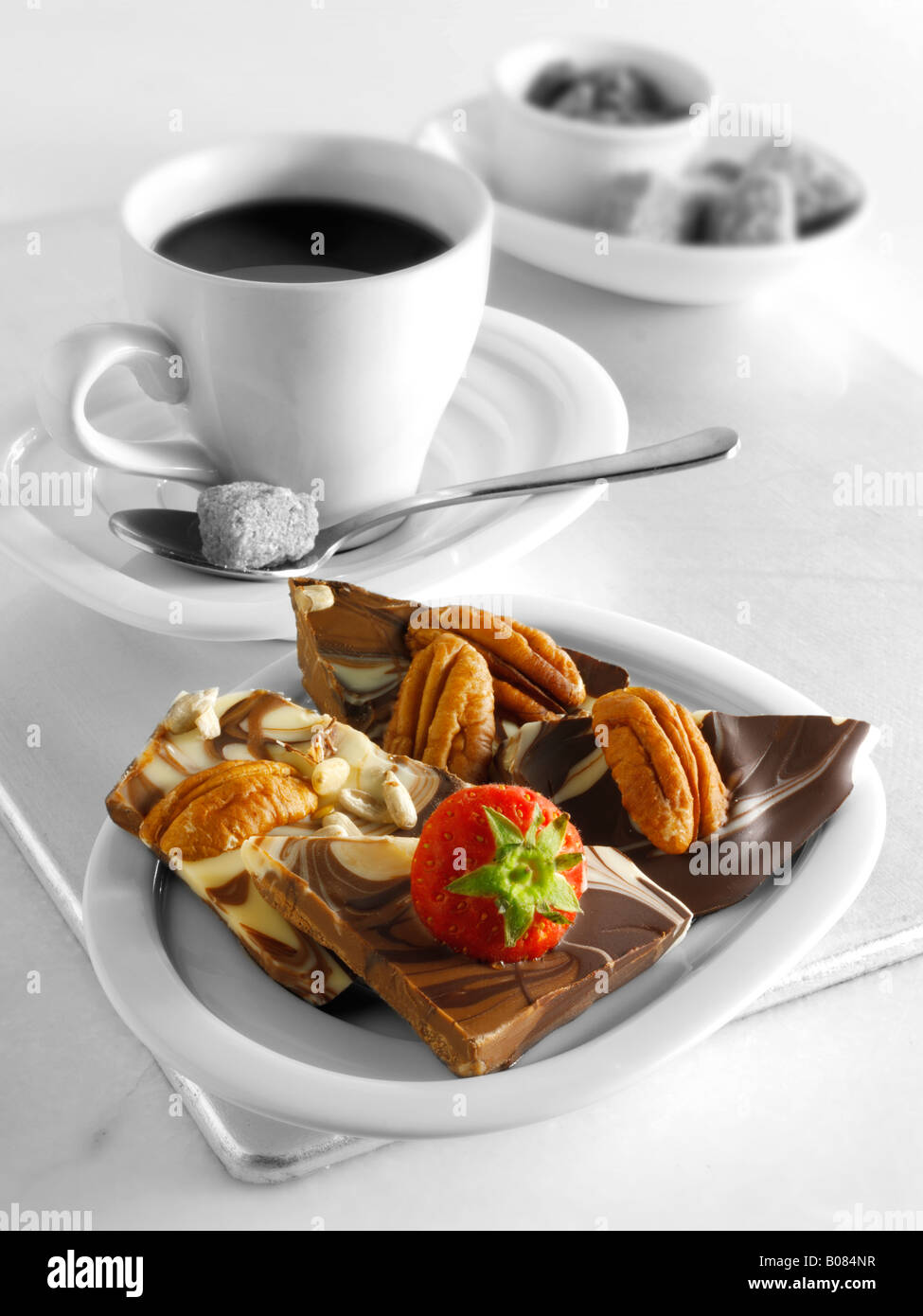 I piccoli quadrati di cioccolato al latte con dadi e fragola con caffè espresso Foto Stock