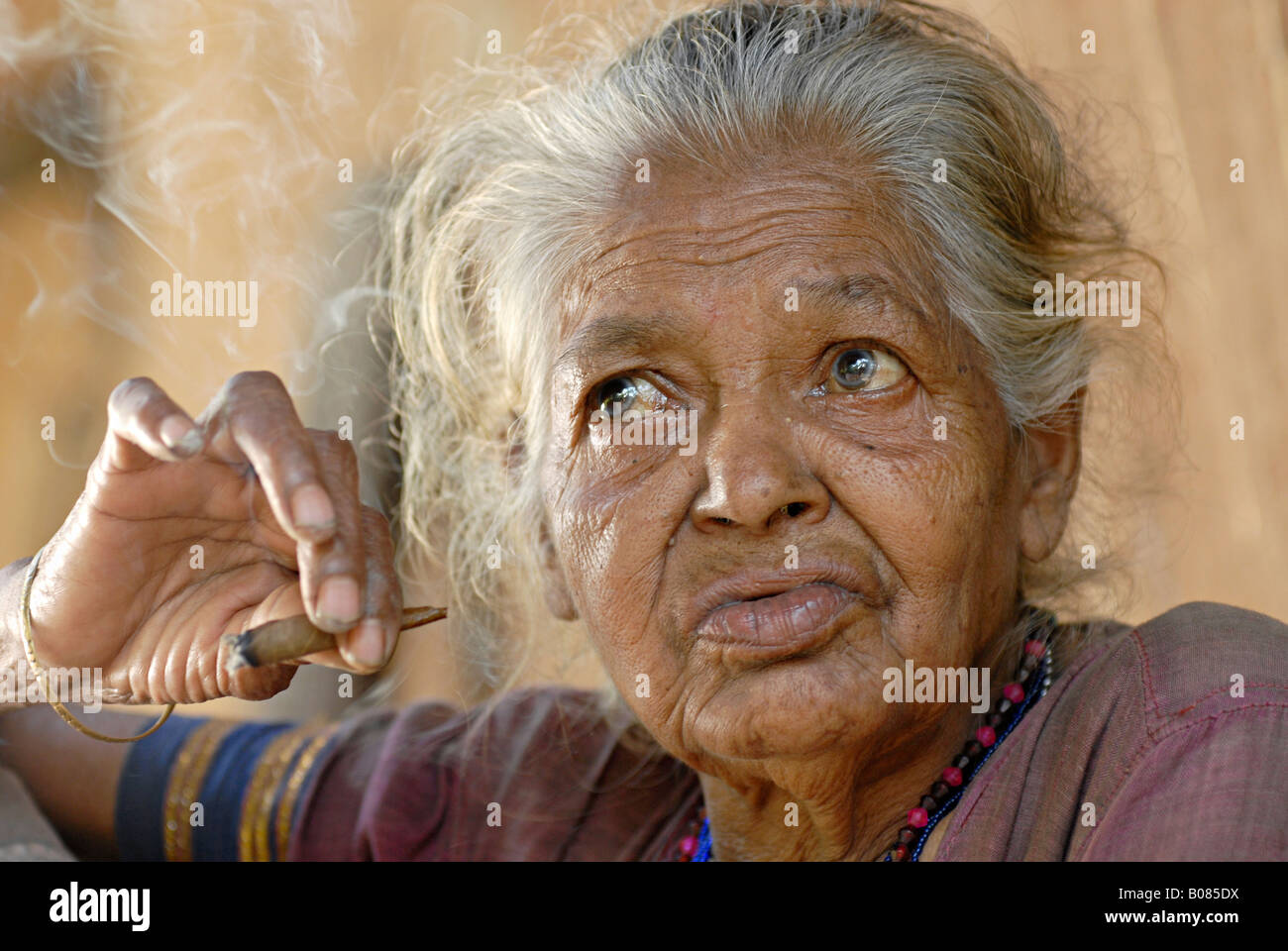 Primo piano di una vecchia donna fumatori bidi, un indiano a mano fatte di sigarette di tabacco o beedi foglie. Warli tribe, Thane, India Foto Stock