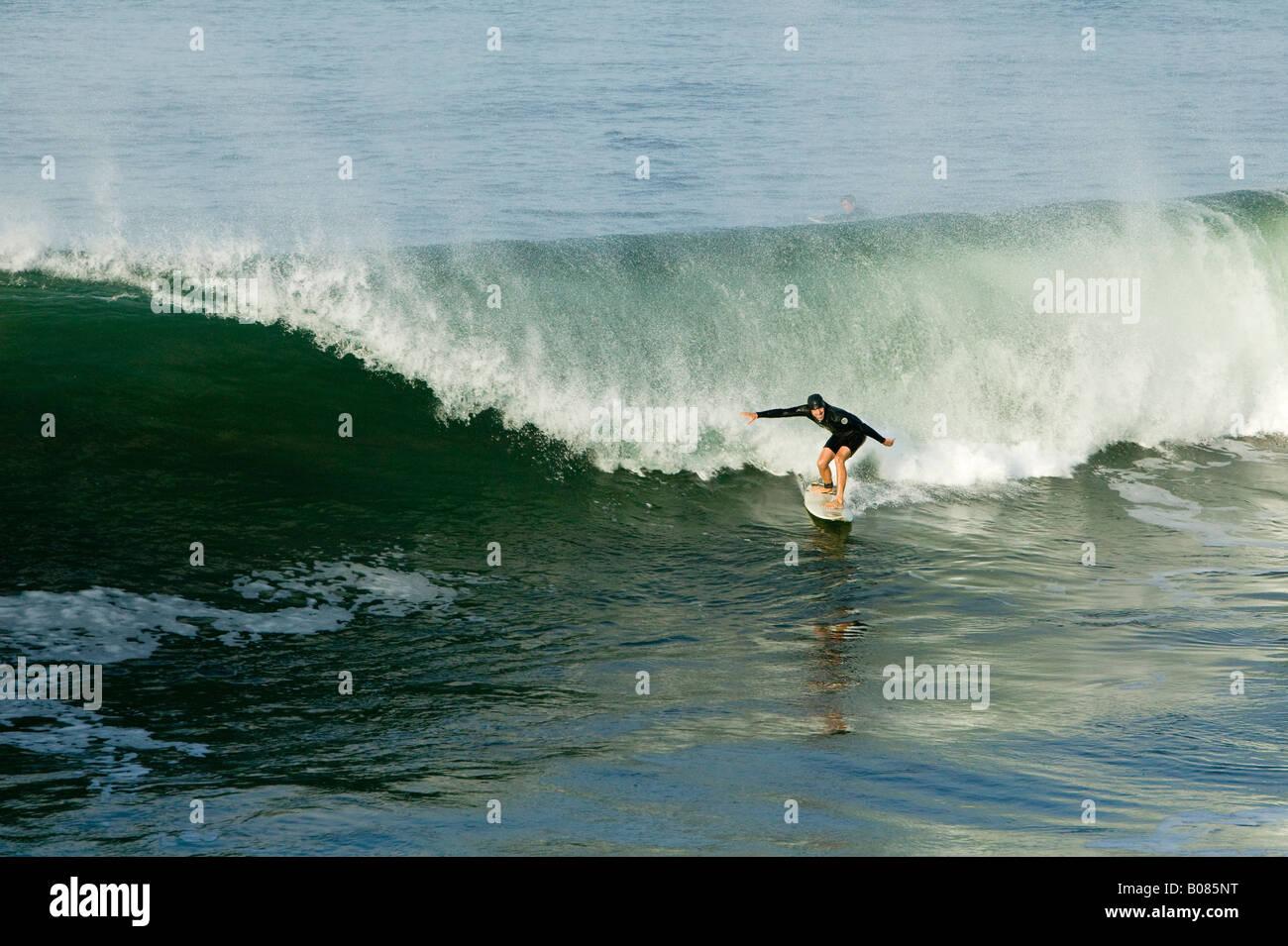 Un surfista cerca di mantenere il suo equilibrio come egli inizia la sua corsa su una bella onda. Foto Stock