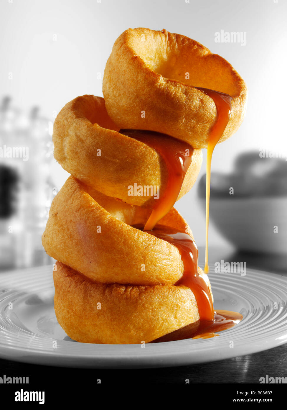 Pila di Yorkshire pudding e sugo di carne in una impostazione tabella pronto a mangiare Foto Stock