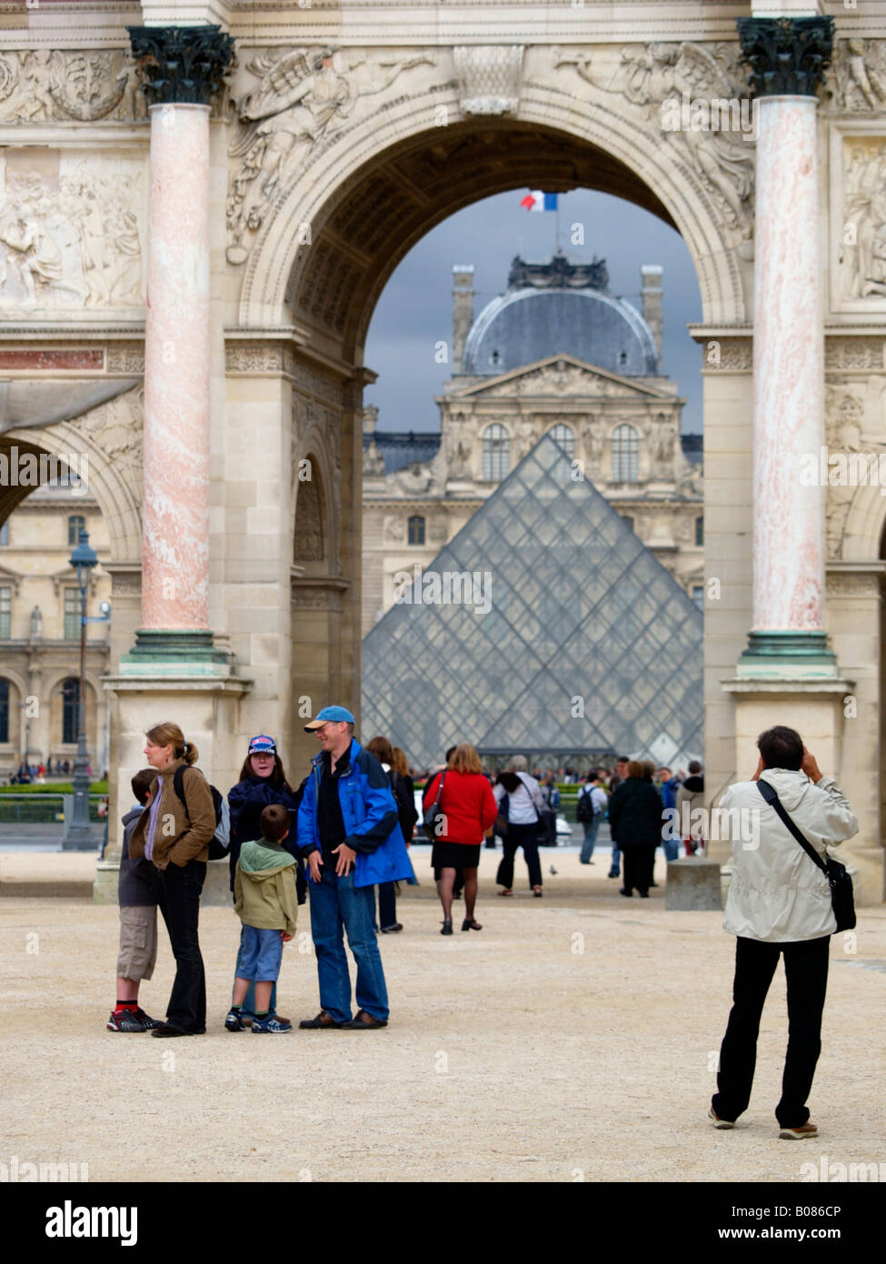 I turisti al museo del Louvre con la famosa piramide visibile attraverso un arco nel palazzo Parigi Francia verticale Foto Stock