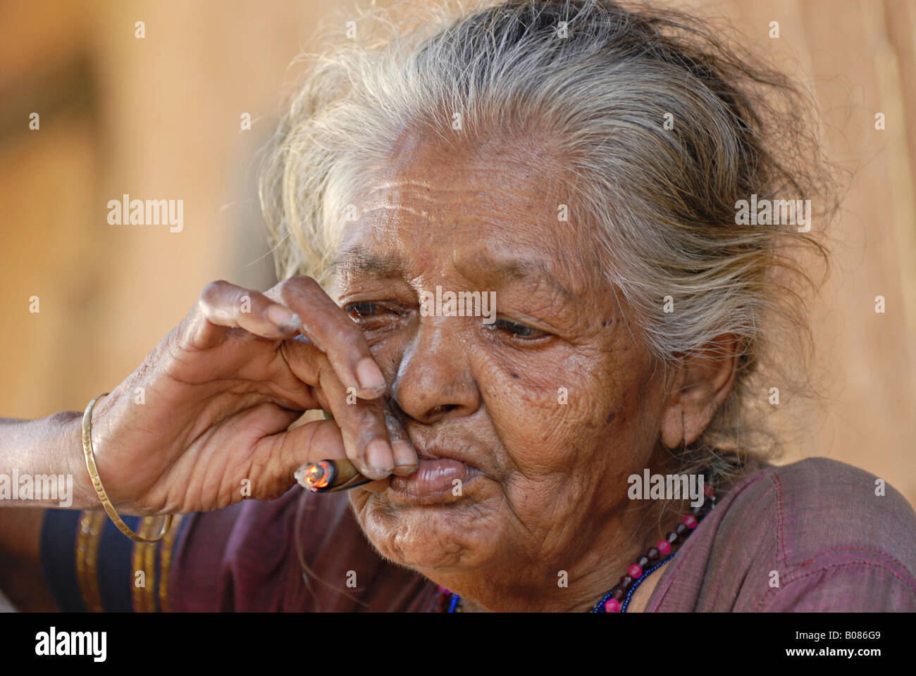 Primo piano di una vecchia donna fumatori bidi, un indiano a mano fatte di sigarette di tabacco o beedi foglie. Warli tribe, Thane, India Foto Stock