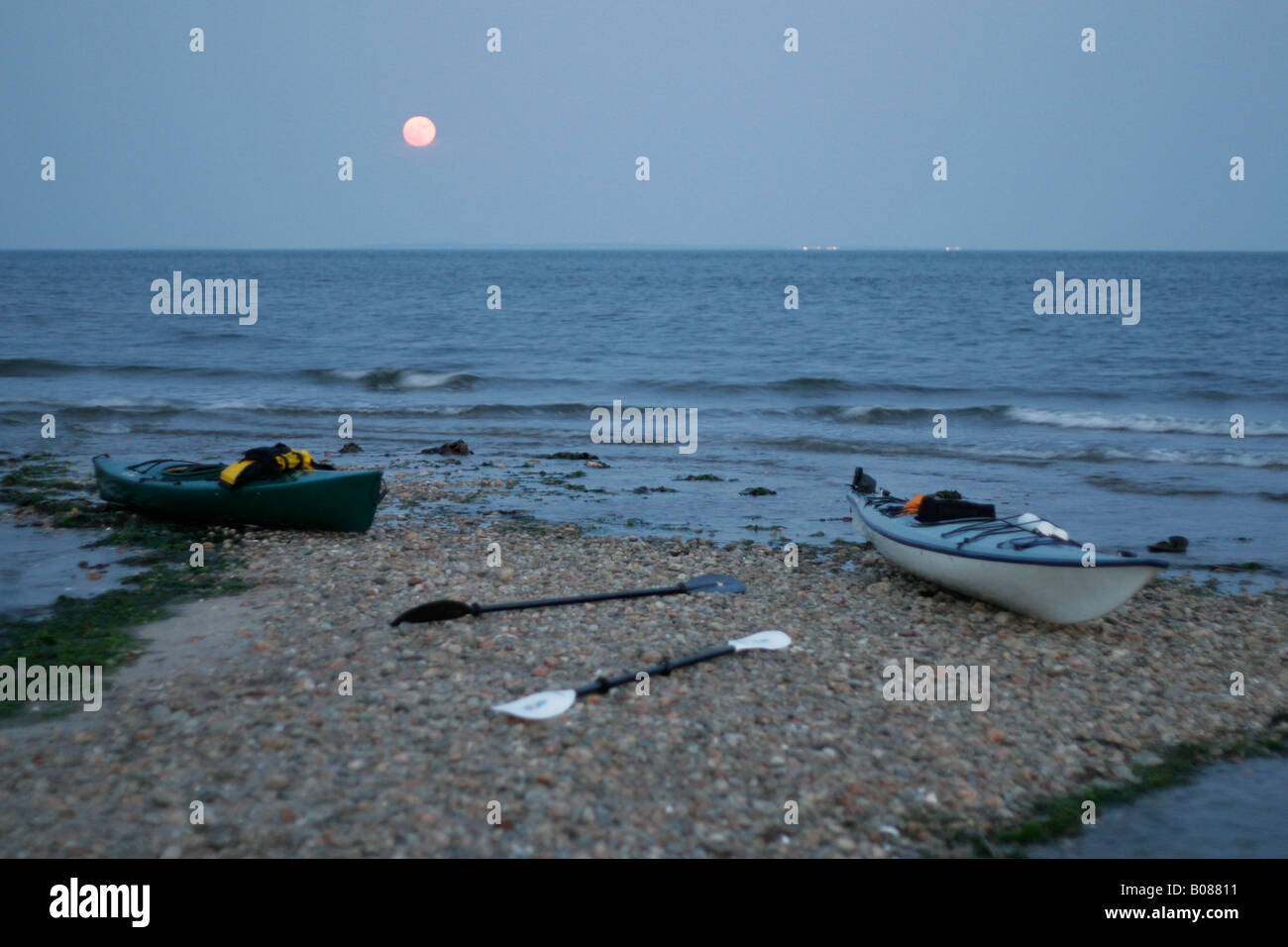 Full Moon Rising oltre due spiaggiata kayak sulla ocean shore Foto Stock