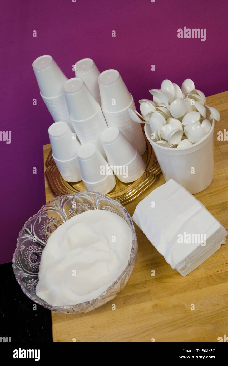 Styrofoam cups cucchiai di plastica di tovaglioli di carta e una tazza di zucchero posa su un tavolo di legno posizione rilasciato Foto Stock