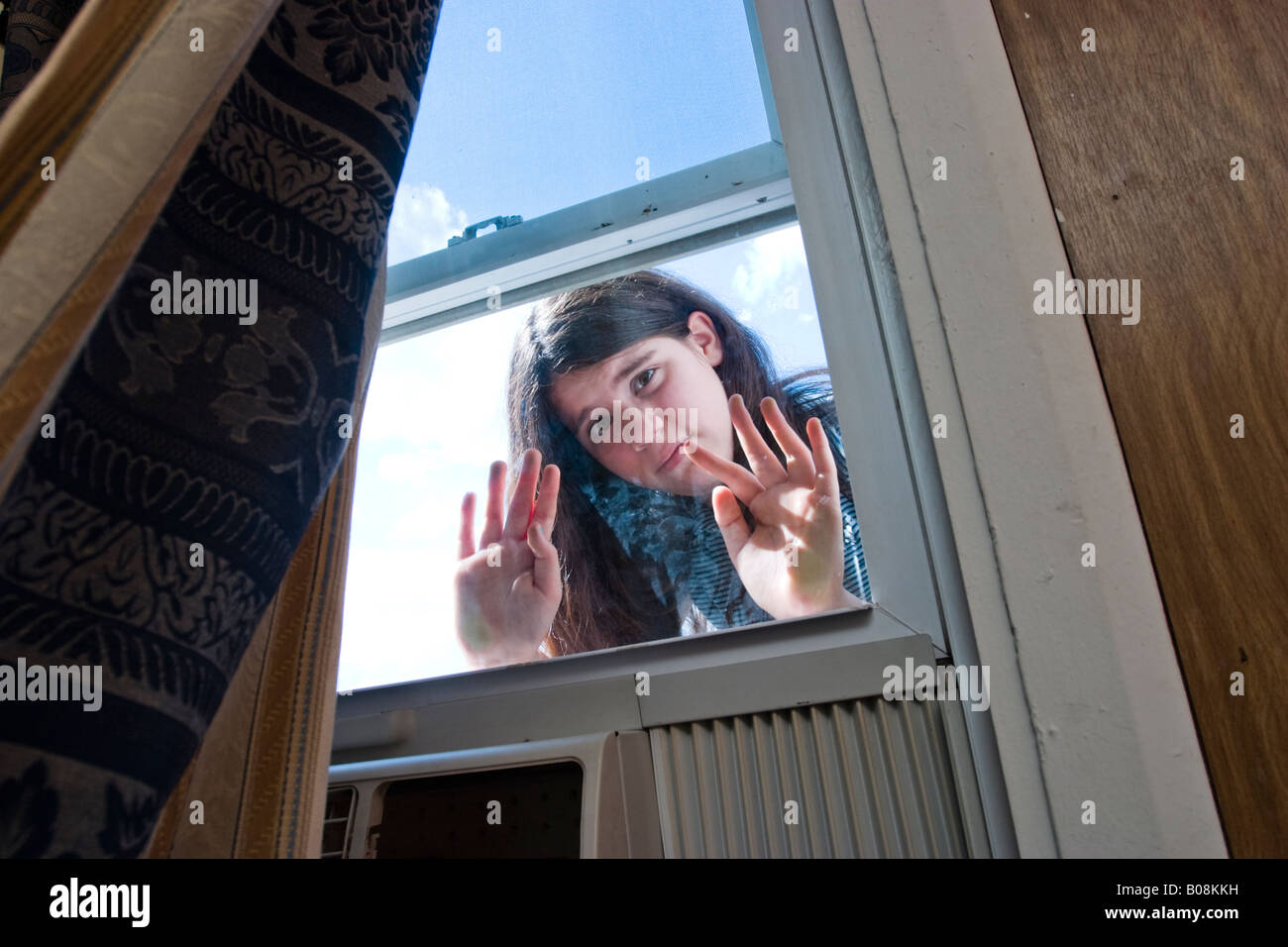 Preteen ragazza di guardare attraverso una finestra in una stanza del motel modello rilasciato Foto Stock