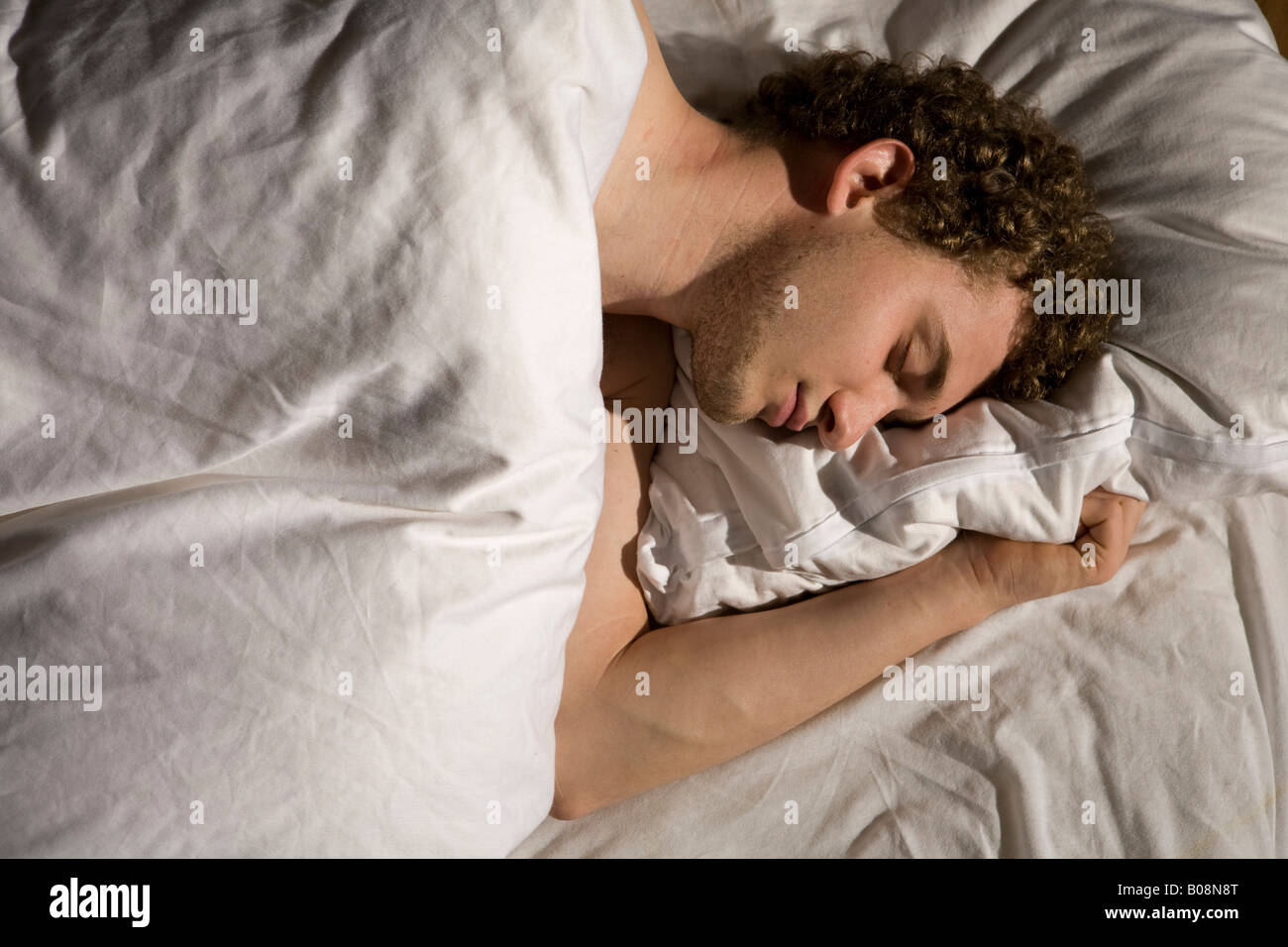 Giovane uomo dorme nel letto Foto Stock