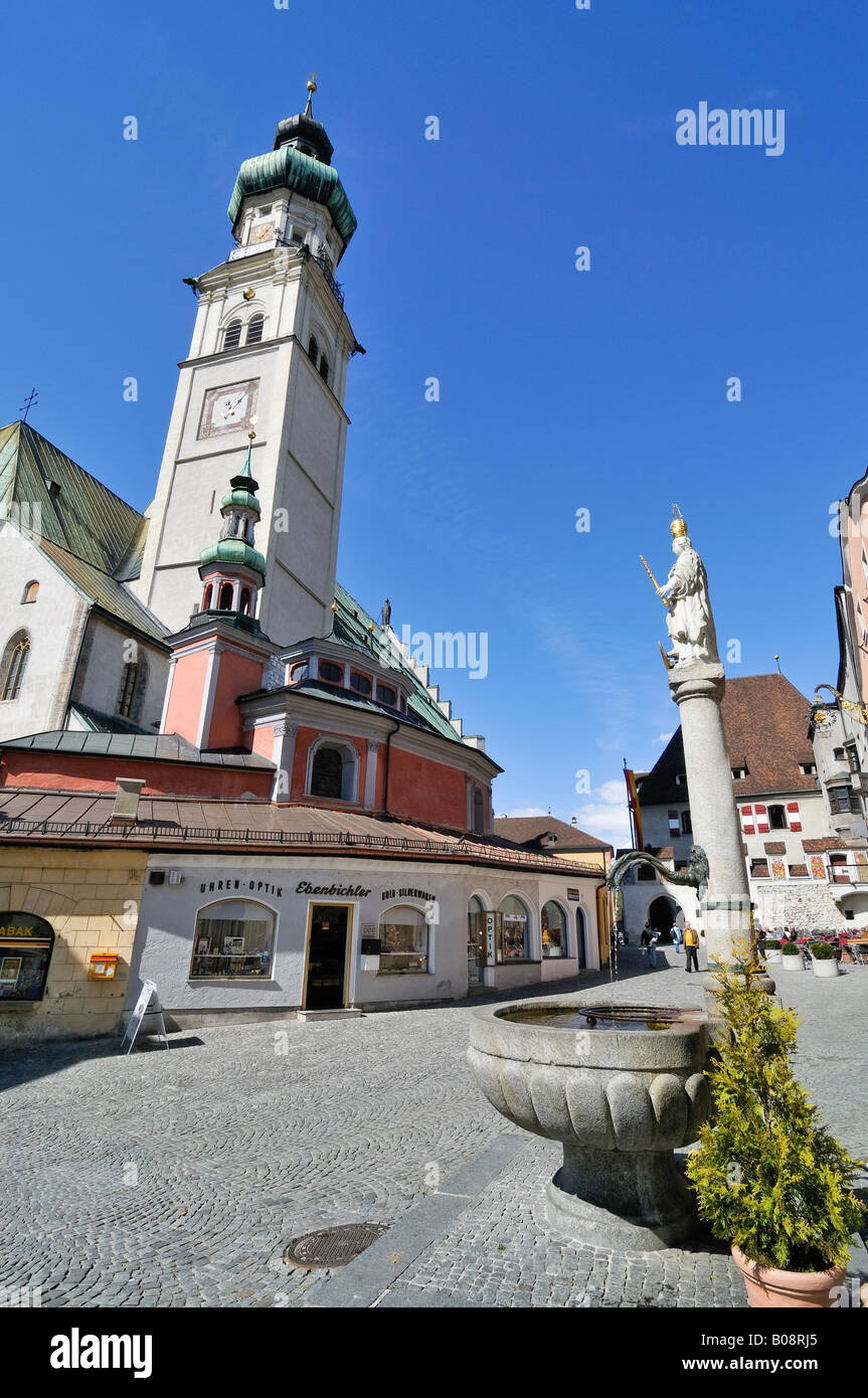 La chiesa il campanile e fontana in strade acciottolate della città alta piazza nel centro storico di Hall in Tirolo, Austria Foto Stock