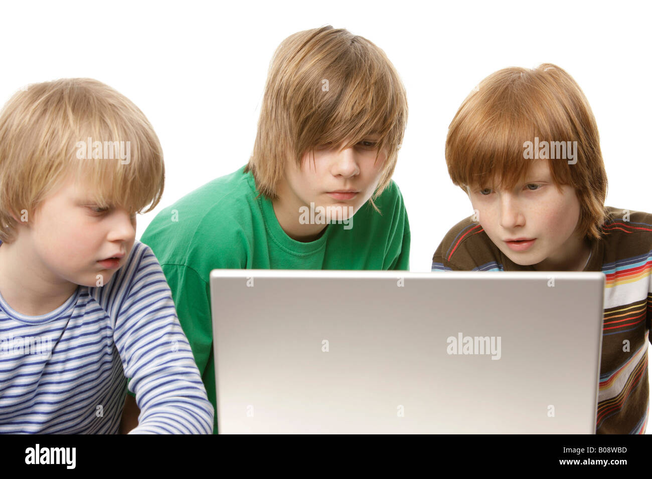 Tre ragazzi seduti davanti a un computer portatile, 10, 12 e 13 anni Foto Stock