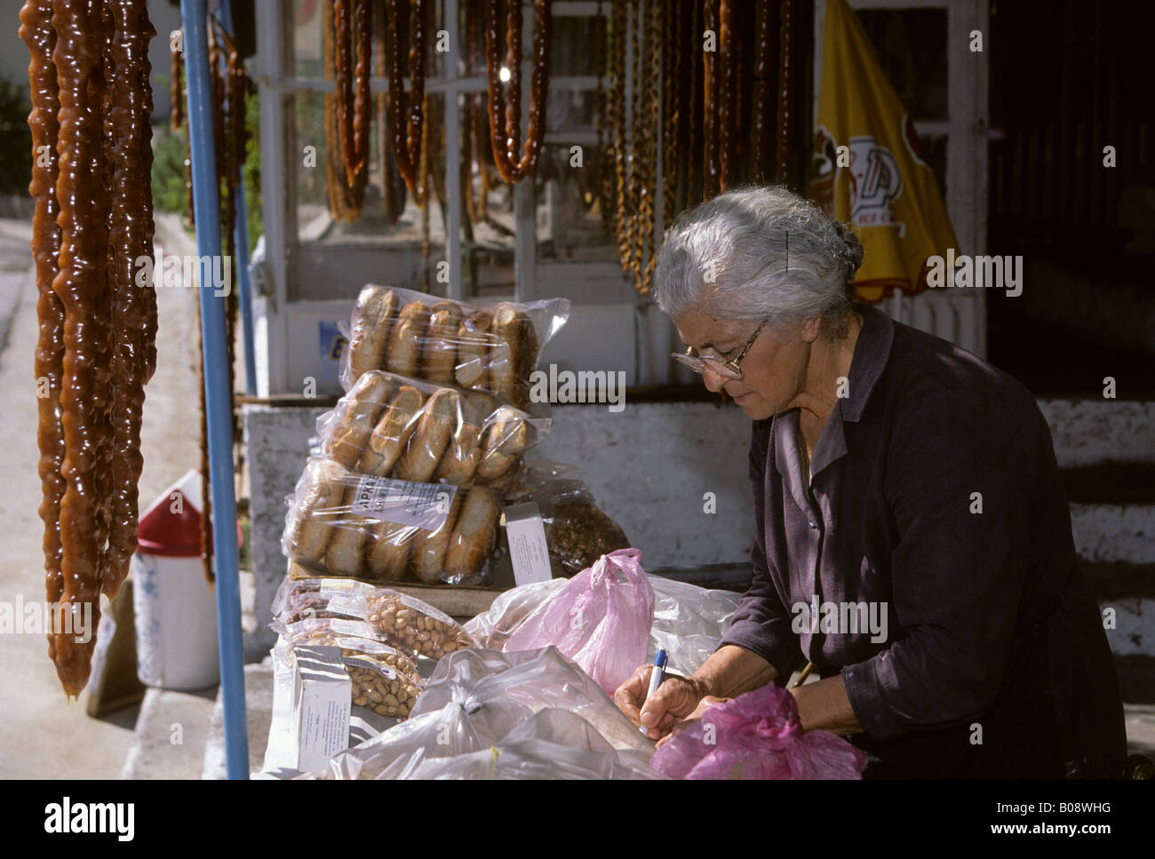 Vecchia donna in un negozio che vende Soutzoukos, specialità cipriote dolce, mandorle e succo d'uva, Lania, Cipro Foto Stock