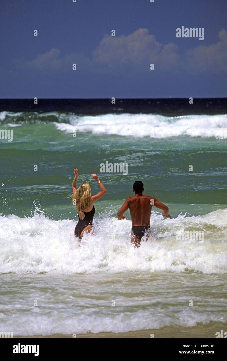 Giovane jumping nelle onde a Surfers Paradise Beach, Gold Coast, Queensland, Australia Foto Stock