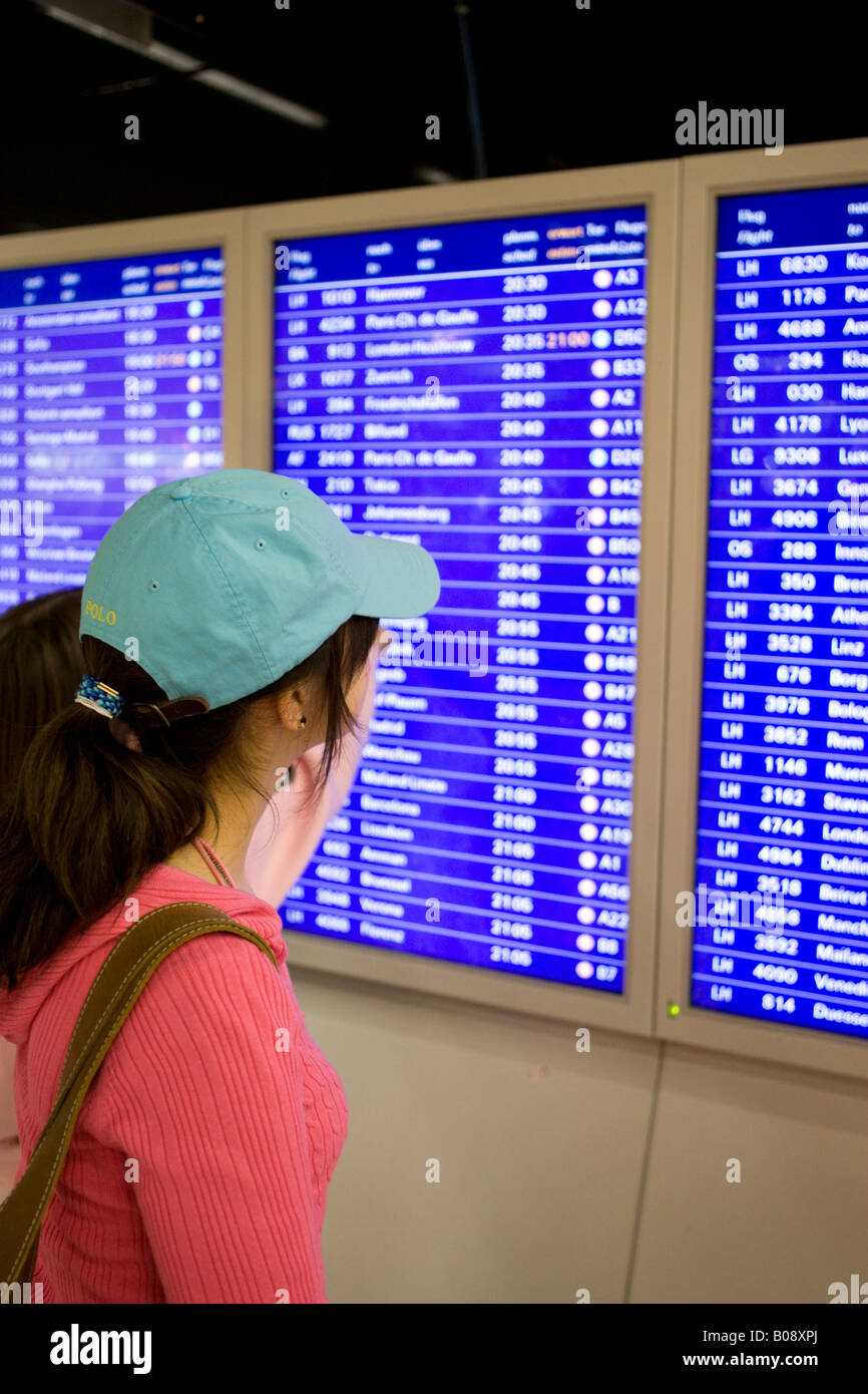Giovane donna la scansione della scheda di partenze, schermate di partenza all'Aeroporto Internazionale di Francoforte Hesse, Germania Foto Stock
