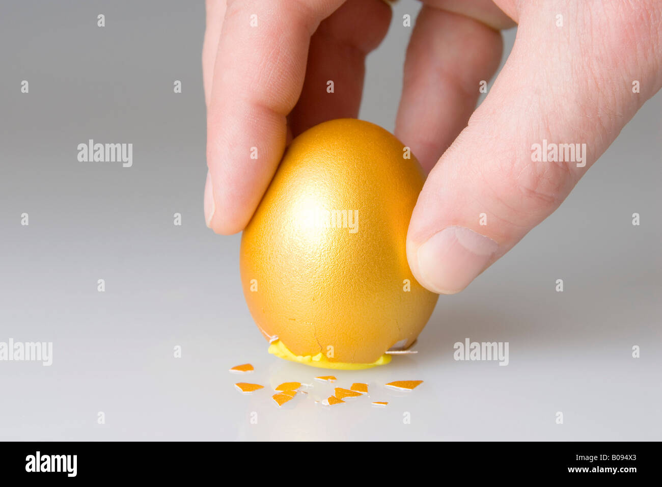 Uovo di Colombo, posizionamento mano golden egg sul suo fondo incrinato Foto Stock