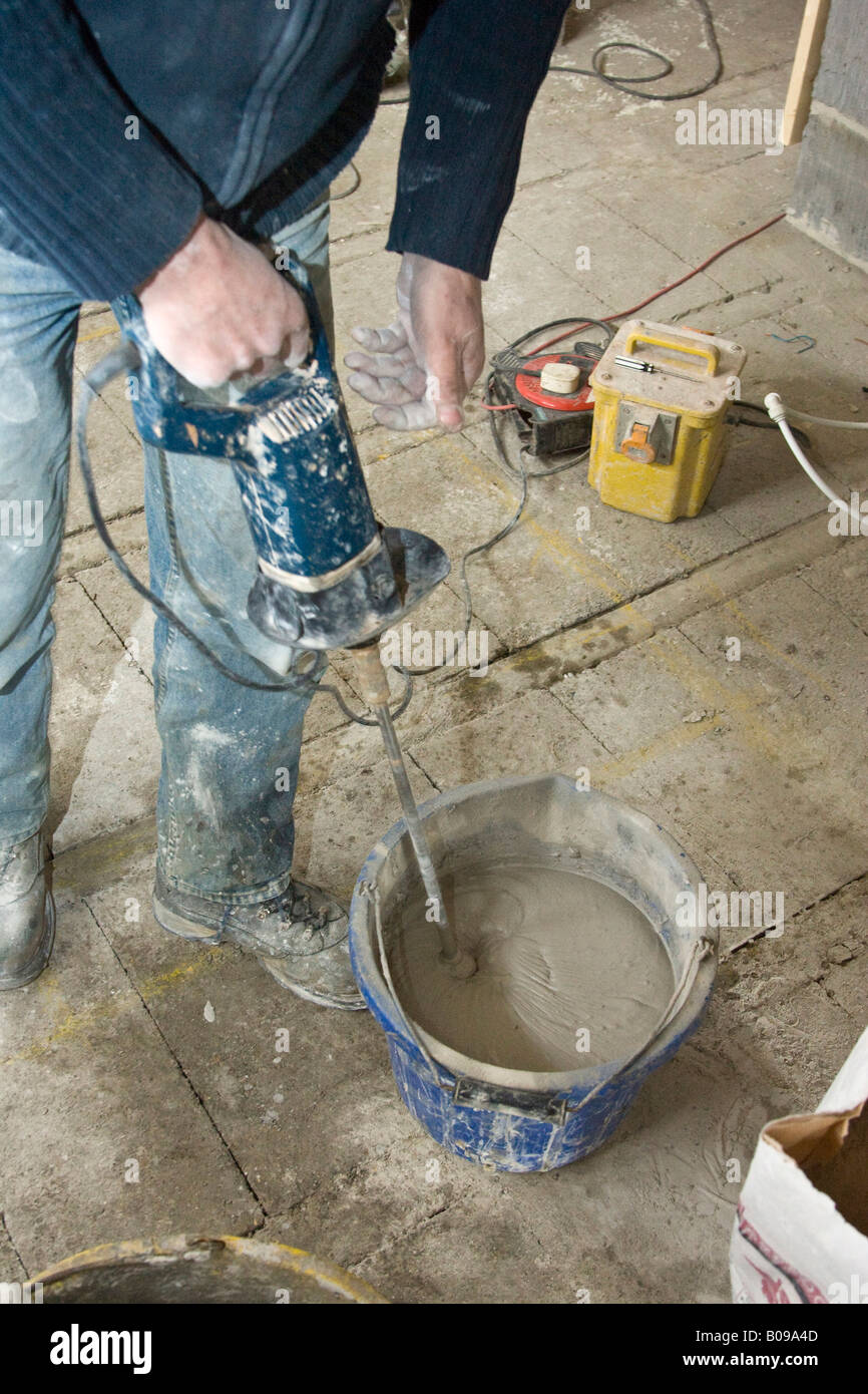 Builder lavoratore la miscelazione di gesso liquido in una benna Foto Stock