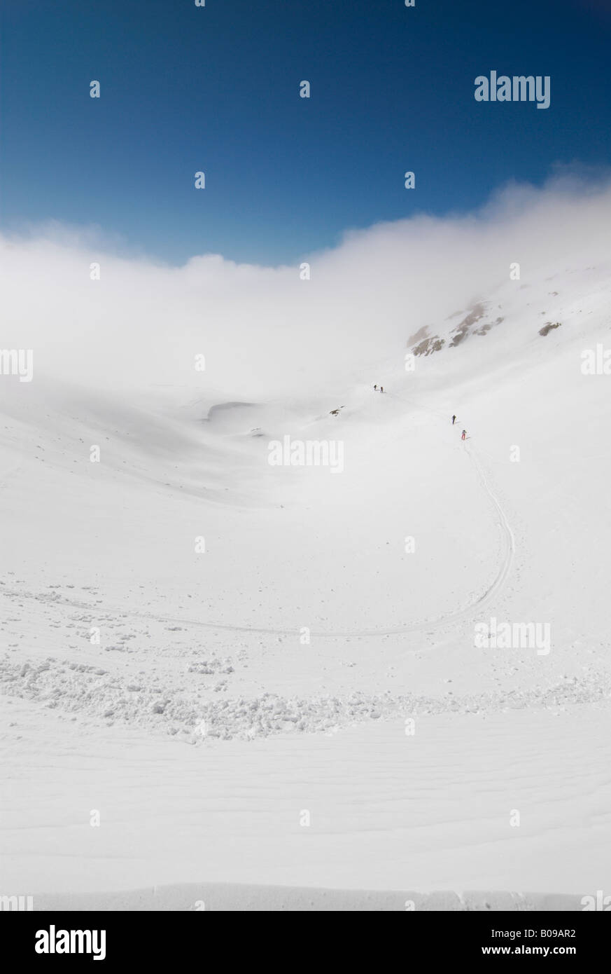 Gruppo di sciatori avvicinando Col Cicle su una soleggiata giornata invernale al di sopra delle nuvole, Les Contamines-Montjoie, Francia Foto Stock