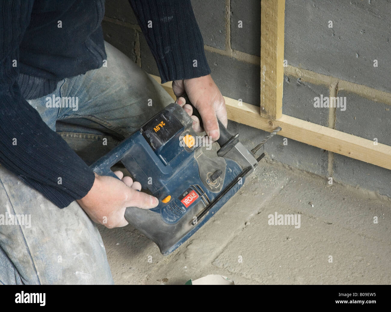 Builder con trapano listelli di raccordo ad una parete interna Foto Stock